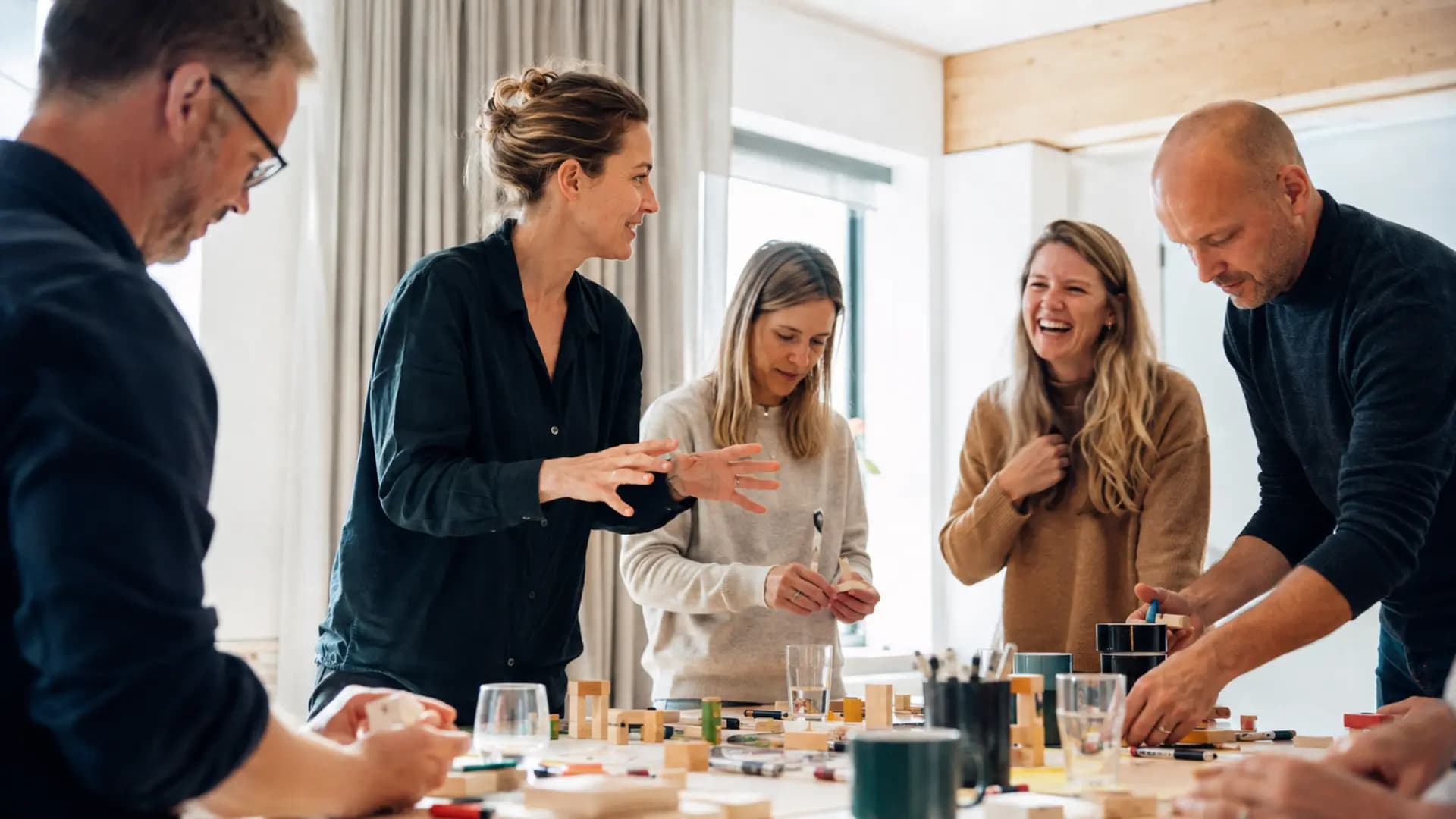 En facilitator leder en levende workshop med deltagere omkring et arbejdsbord